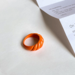 Close-up of a French vintage orange enamel croissant-style open ring on white background