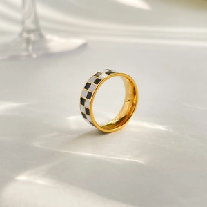 Detailed view of gold checkerboard ring with black and white enamel and shadow accents