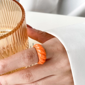 Close-up of a glossy orange twisted croissant ring for women in a vintage French style