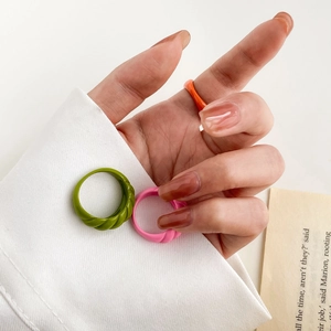 Macro detail of three retro candy-colored resin rings with twisted woven textures