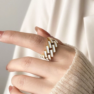 Detail of a wide gold ring with white enamel checkerboard pattern worn on a hand