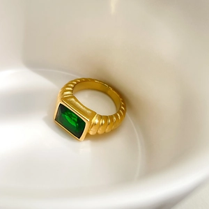 Detail of vintage gold-toned twisted band ring featuring a large rectangular emerald stone