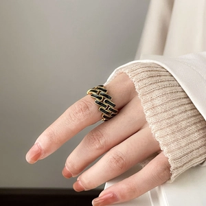 Detailed view of a gold hollow-out ring featuring a black enamel checkerboard pattern