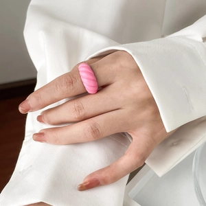 Detail of pink candy-colored bread texture ring with spiral design on finger