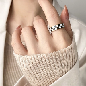 Close-up of a gold hollow chain ring with black and white checkered enamel finish