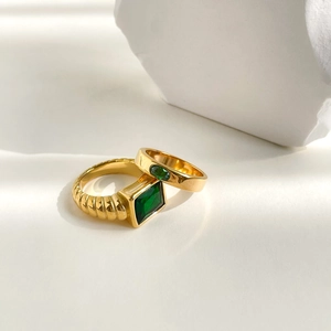 Gold plated ring set featuring emerald cut and oval green zircons on white stone base