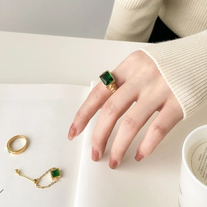 Detailed close-up of emerald-cut green gemstone rings with elegant gold chain link accents