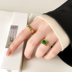 Gold-plated ring set with emerald green zircons and chain style on model's finger