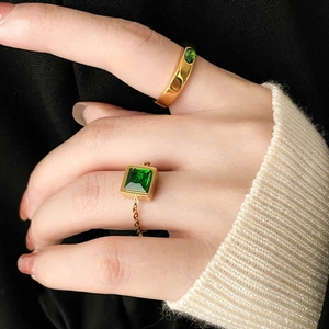 Macro shot of two gold plated rings featuring emerald cut green zircon on hand display