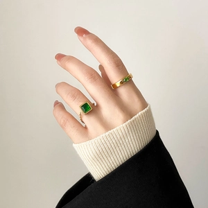 Detail of gold chain ring with square emerald zircon and wide band oval green gem