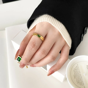 Detail view of gold emerald ring with oval green gemstone worn by a model