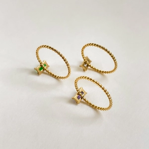 Vue détaillée de trois bagues dorées torsadées avec émeraude et zircon violet baguette