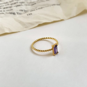 Vue détaillée d'un zircon violet à coupe émeraude sur une bague torsadée dorée