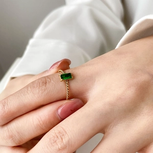 Bague torsadée en or avec zircon vert taille émeraude, portée par un mannequin