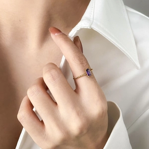 Vue détaillée d'une bague torsadée dorée ornée d'un zircon rectangulaire violet