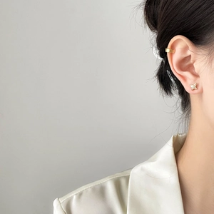 Detail shot of a butterfly stud earring and hexagonal ear cuff set in gold finish