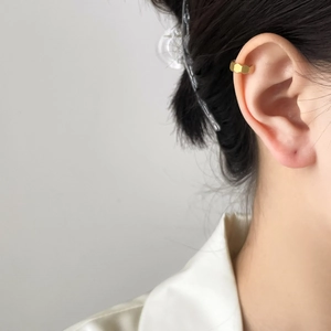 Detailed view of a gold hexagonal honeycomb ear cuff worn on the upper ear cartilage
