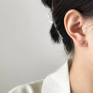 Detailed close-up of a zircon butterfly ear cuff on a model with gold plating finish