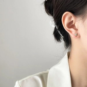 Close-up of zircon butterfly stud earring in gold finish worn by a model for scale
