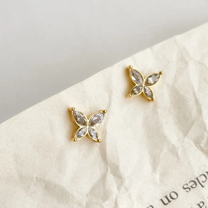 Elegant gold butterfly stud earrings with marquise zircon on a minimalist paper background