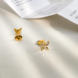 Close-up of golden butterfly earrings with marquise zircon stones on white background
