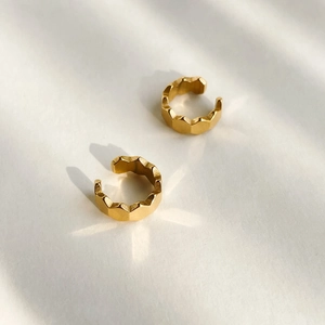 Macro shot of gold-plated honeycomb cartilage cuffs with geometric faceted textures