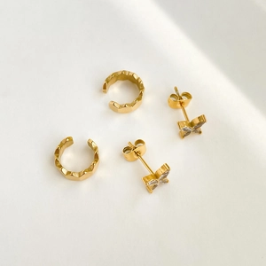 Detail view of gold butterfly stud earrings and geometric textured ear cuff set
