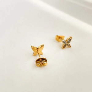 Close-up of gold stud earrings with four-leaf zircon stones and butterfly backings