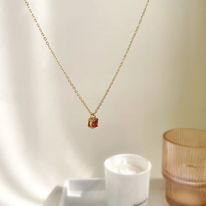 Macro detail of a 1-carat red zircon pendant on a delicate gold chain necklace