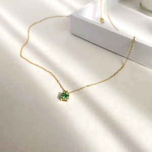 Detail of 1 carat green zircon pendant on gold chain with elegant light and shadow