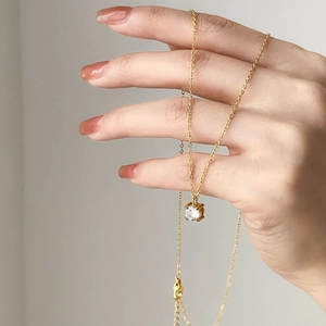 Minimalist gold necklace featuring a one-carat round zircon pendant in four-prong setting
