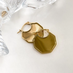 Detailaufnahme goldener geometrischer Ohrringe mit strahlender Sonnenstruktur