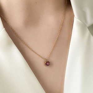 Macro close-up of a 1-carat red zircon pendant necklace on gold chain worn by a model
