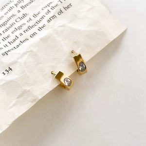 Goldene fächerförmige Ohrringe mit ovalem Zirkon auf Vintage Buchhintergrund