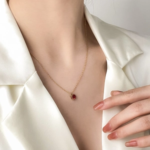 Elegant 18K gold chain with a sparkling round ruby pendant on white satin shirt