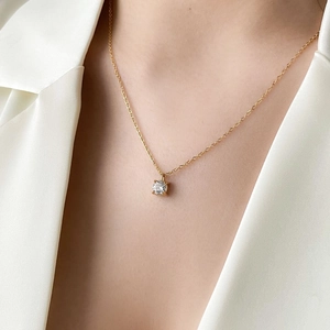 Elegant gold pendant necklace with round zircon stone worn on a silk blazer