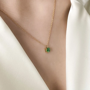 Close-up of a 1-carat green zircon pendant necklace worn on a woman's collarbone
