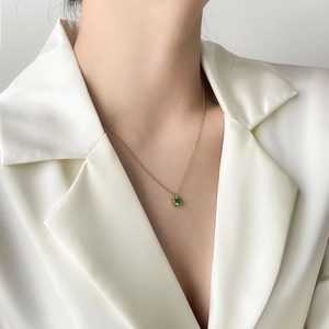 Close-up of a square cut emerald zircon pendant on a gold necklace worn by a model