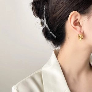 Detailansicht goldener fächerförmiger Ohrringe und Haarklammer an einem Model