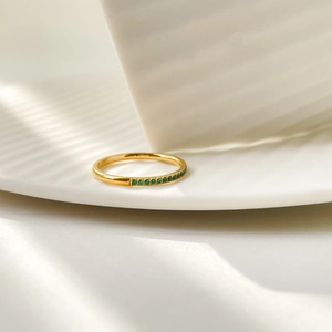 Macro shot of gold-plated titanium ring featuring half-circle row of green zircons