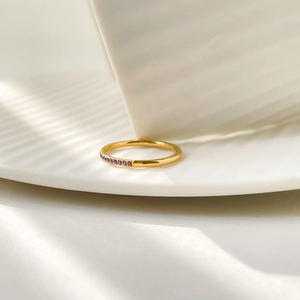 Macro detail of gold plated steel ring with purple zircon stones in soft window light