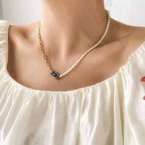 Détail du collier vintage avec pierre carrée noire, chaîne dorée et perles blanches sur modèle