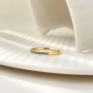 Detailed shot of a gold-plated titanium ring with ten round blue turquoise zircons
