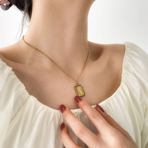 Collier vintage doré avec pendentif rectangulaire et bordure en émail noir sur mannequin