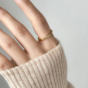 Close-up of gold titanium ring with paved zircons worn on index finger with cozy knit cuff