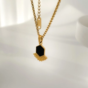 Détail du collier doré avec pendentif hexagonal noir et élément en éventail élégant