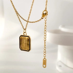 Vue macro d'un collier en or 18 carats avec gravure florale et bordure en émail noir