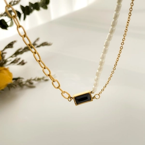 Détail du collier avec pierre noire carrée et chaîne asymétrique en perles élégantes