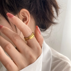 Bague multicouche dorée minimaliste aux lignes abstraites sur le doigt du modèle