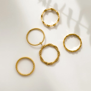 Close-up of set of five gold geometric twisted and beaded stackable fashion rings